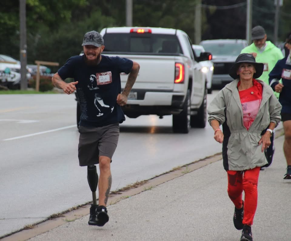 Marilyn Farnworth in red and a raincoat taking part in the Terry Fox Run alongside another participant.