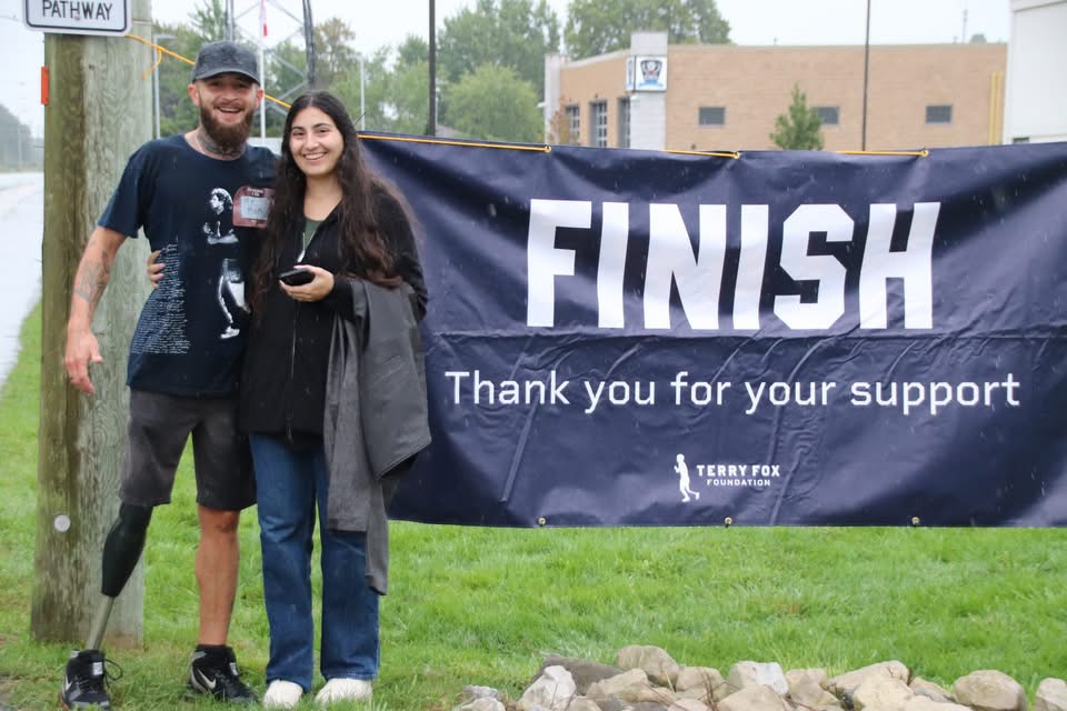 Two Terry Fox Run participants standing beside the finish banner.